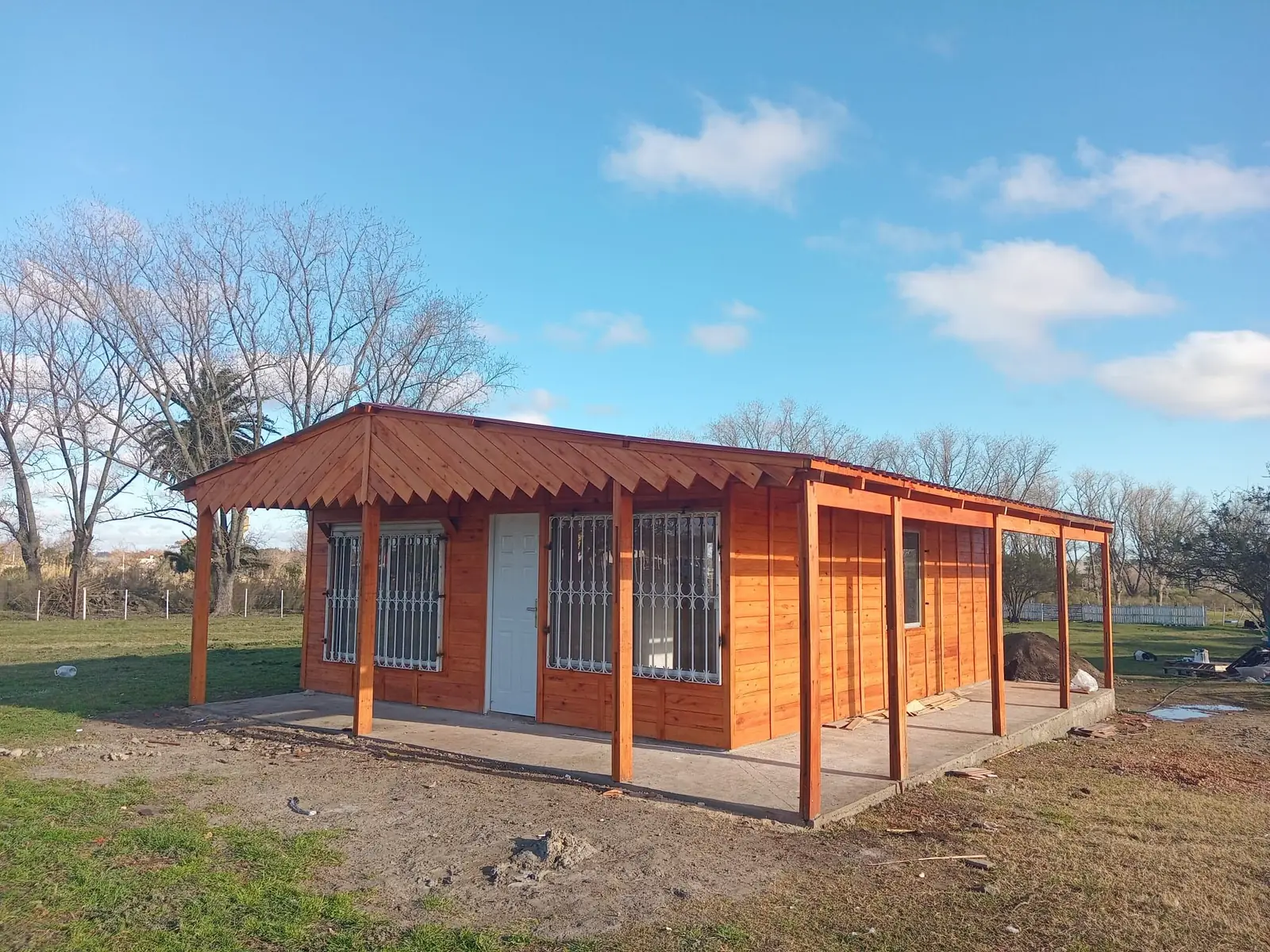 Vivienda de madera terminada con galería techada y aberturas de aluminio, de frente