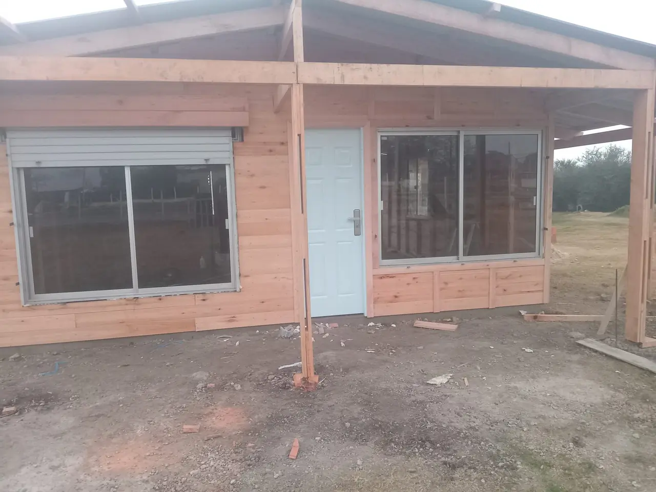 Vivienda de madera con ventanales corredizos de aluminio y cortinas de enrollar