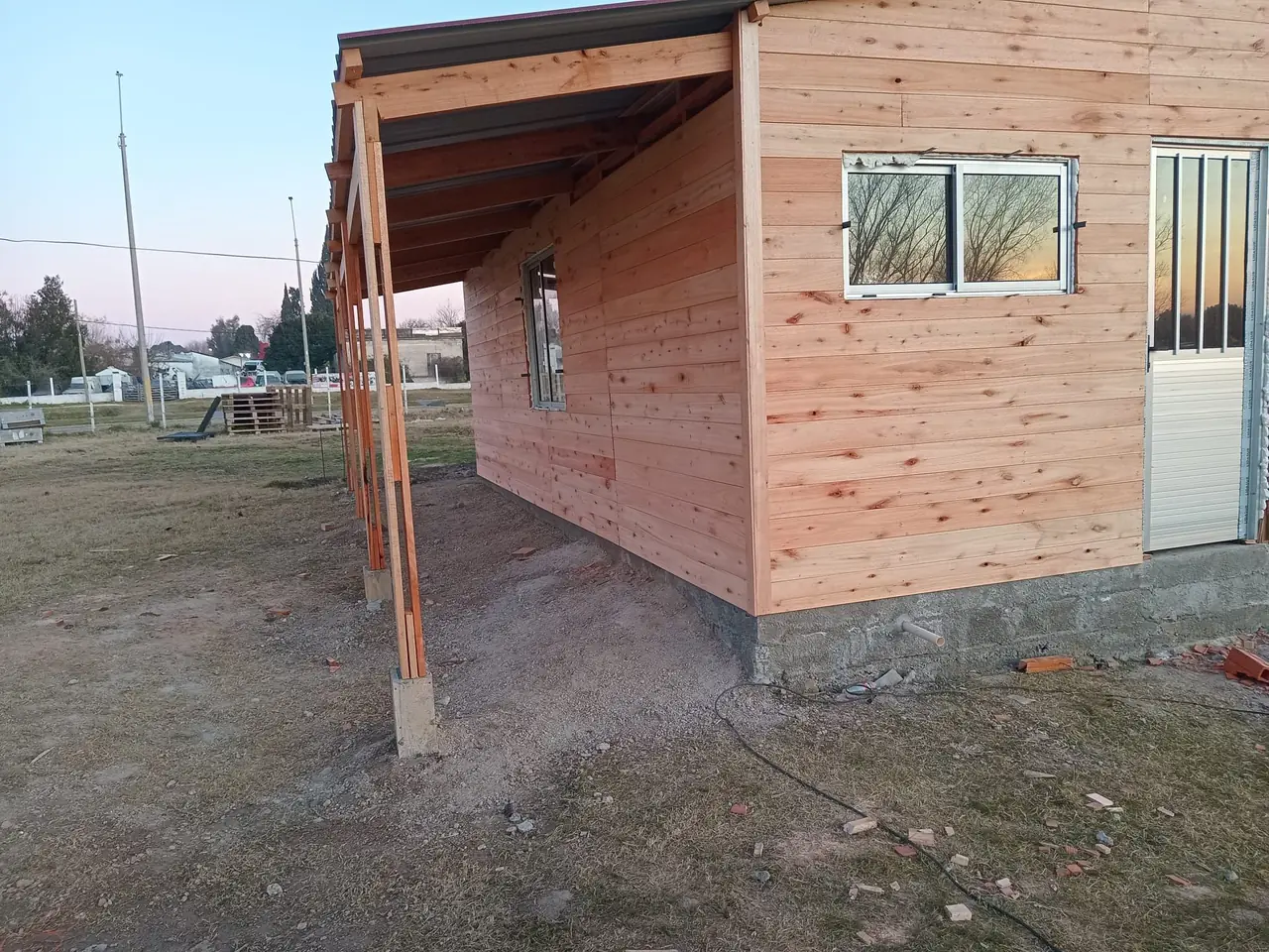 Lateral de una vivienda de madera con la galería techada y ventana de aluminio