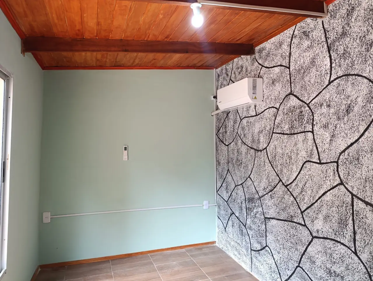 Sala terminada con aire acondicionado, piso cerámico y pared en piedra