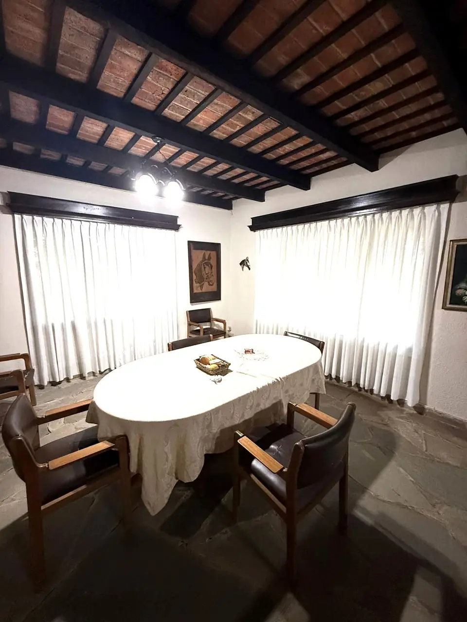 Cortinas tradicionales de tela en las ventanas de un comedor con techo de madera