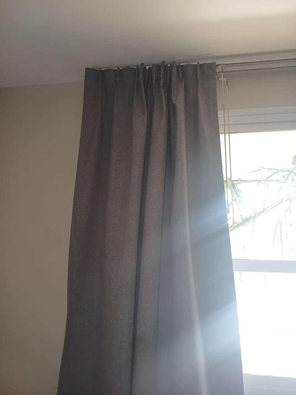Cortina tradicional blackout gris, con pliegues, corrida junto a la ventana